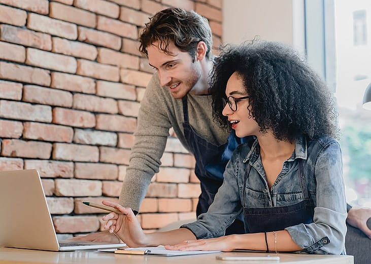 Two young coffee shop workers review business reports.
