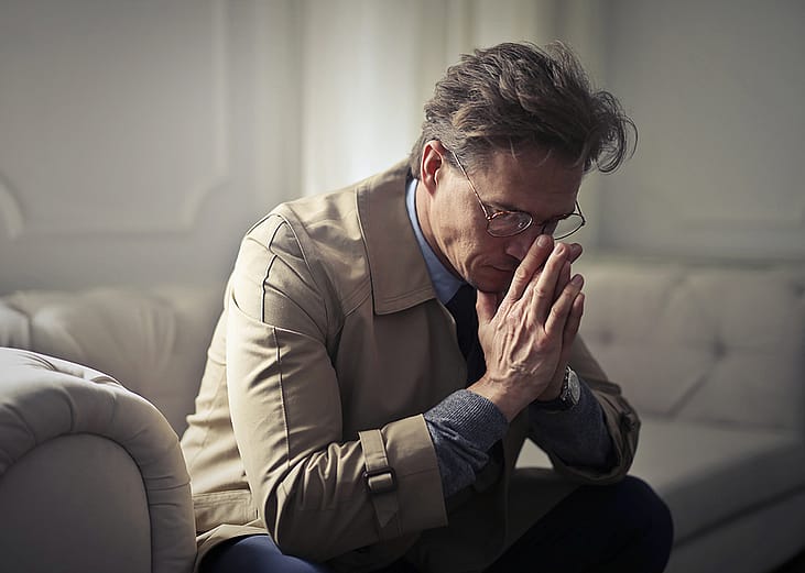 A man sitting on a sofa in deep contemplation