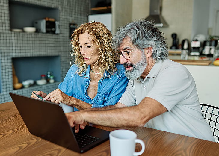 A senior couple at home purchasing an item online with a credit card.