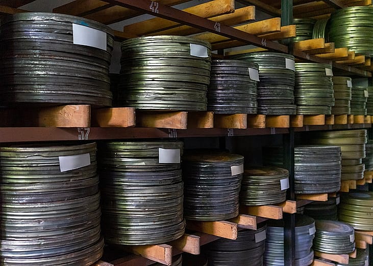 Stacks of metallic film reels on wooden shelves.