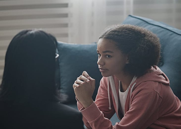 A teenager listening to a youth counselor during a psychological support session in a clinic.
