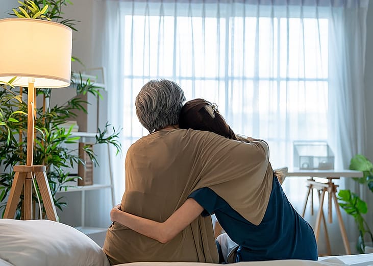 Rear view of an elderly mother comforting her daughter at home.