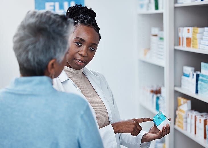 A black female pharmacist assisting an elderly patient with medication.