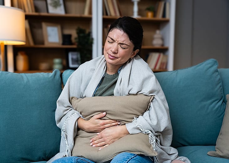 A woman at home experiencing stomach cramps.