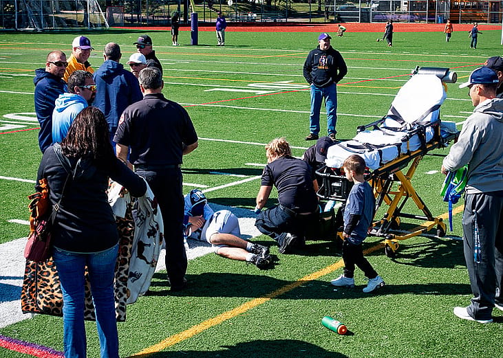 A medic team attends to an injured football player laying on the ground