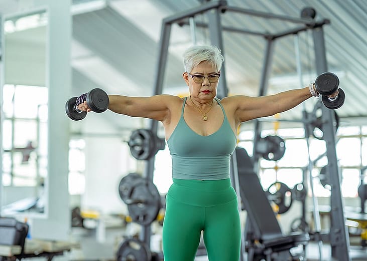 A senior woman working out with weights at the gym.