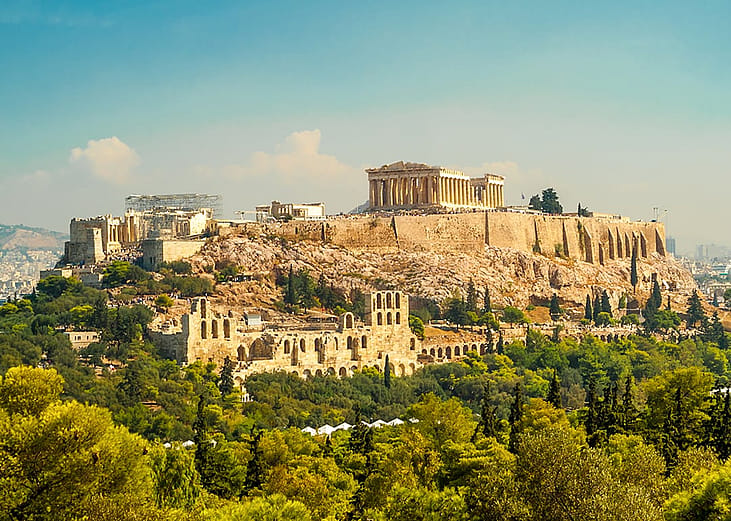 A view of the scenic Acropolis of Athens featuring the Parthenon at the top, ancient slopes, and elevated terrain in Greece.