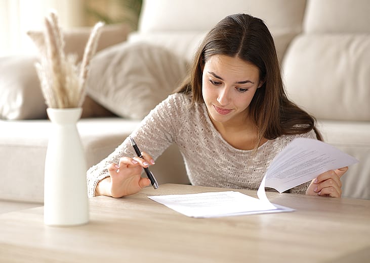 A person reviewing the coverage and cash value of her life insurance policy at home.