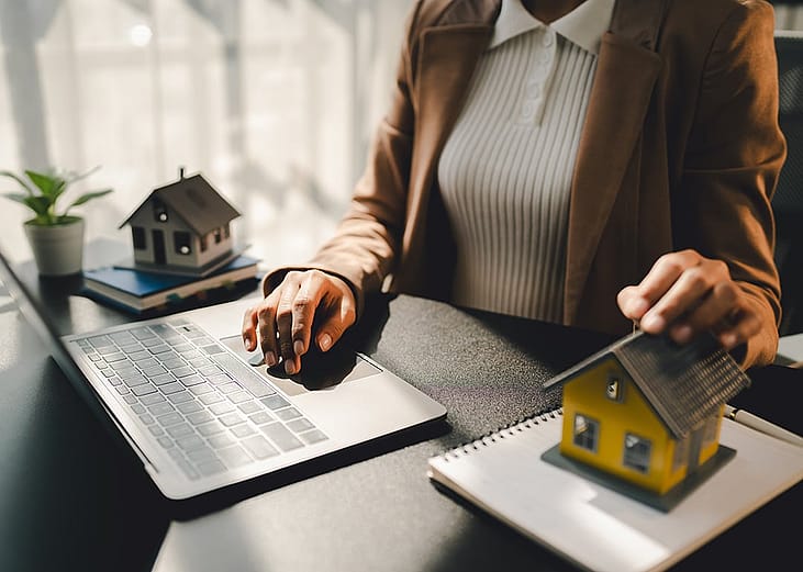A real estate agent showing model homes to clients during a property marketing pitch in an office.