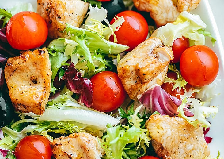 A chicken salad dish with cherry tomatoes.
