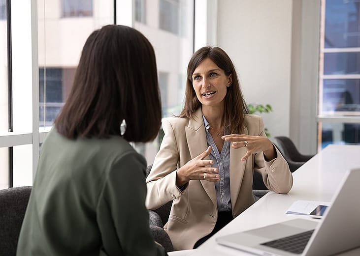 Two businesswomen engaged in a discussion at a meeting.