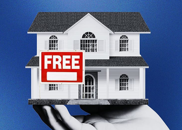 A person's hand holding a two-storey model house with a Free sign.