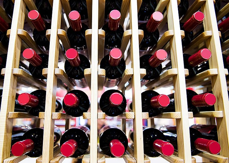 A group of red wine bottles stacked on wooden racks.
