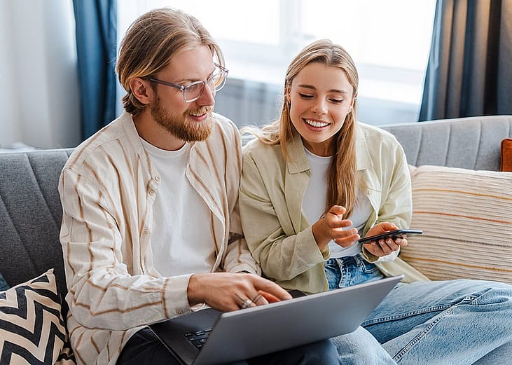 A young couple at home browsing property listings online.