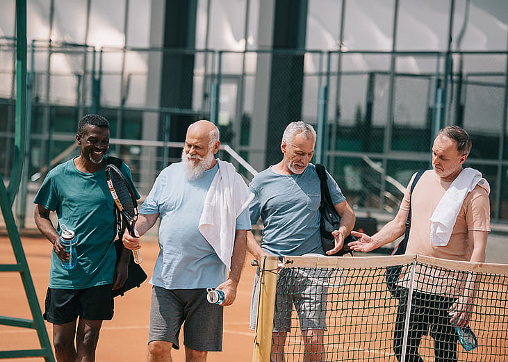 A diverse group of senior men at a tennis court.