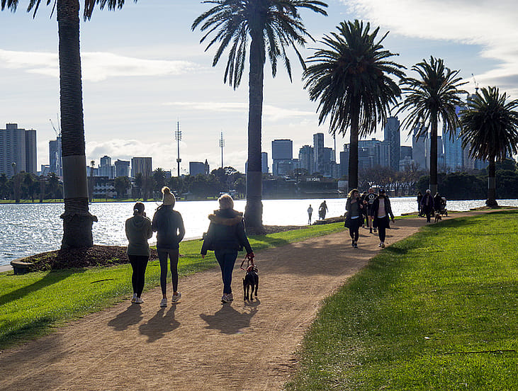 Groups of people in face masks exercise, running and walking around Albert Park Lake during COVID-19 lockdown.