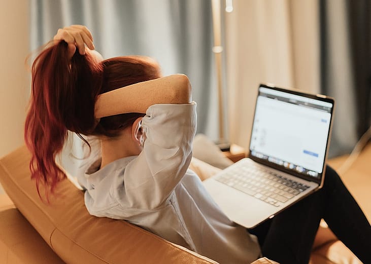 A young woman working at home and reviewing info using a laptop.