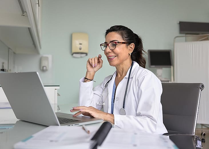 A happy female doctor talking to a patient online using teleconsultation.