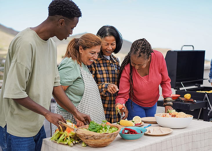 A diverse family preparing food for the barbecue grill outdoors.