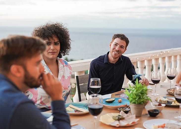 Group of diverse young friends enjoying dinner at a home patio.
