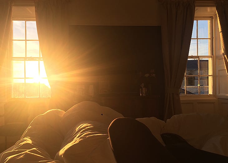 The morning sun casting a golden and warm glow through a bedroom's window.