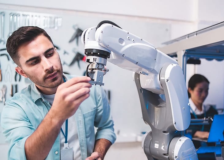 Engineers working on a robot arm at a lab.
