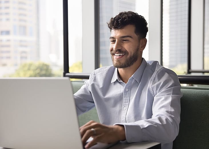 A happy employee typing on a laptop.