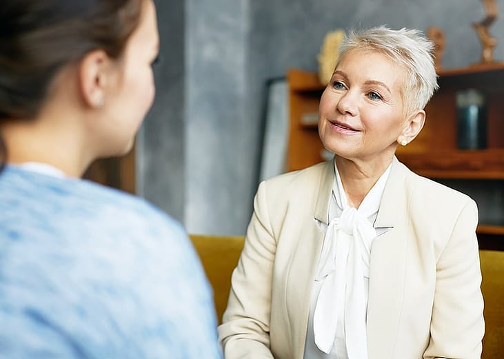 An HR advisor discussing their company's AI adoption and progress to a people manager in the office.