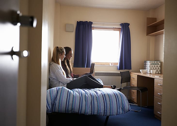 Students working on class requirements inside their dorm in a campus accommodation.