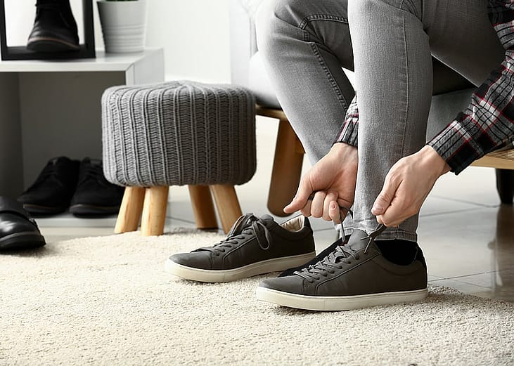 A person putting on sneakers inside a dressing room.