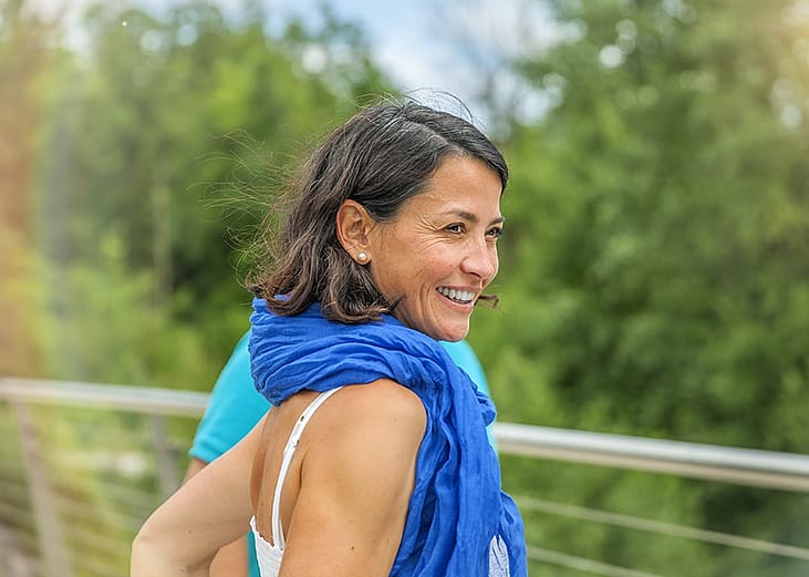 A person smiling and posing for a photo in the park.