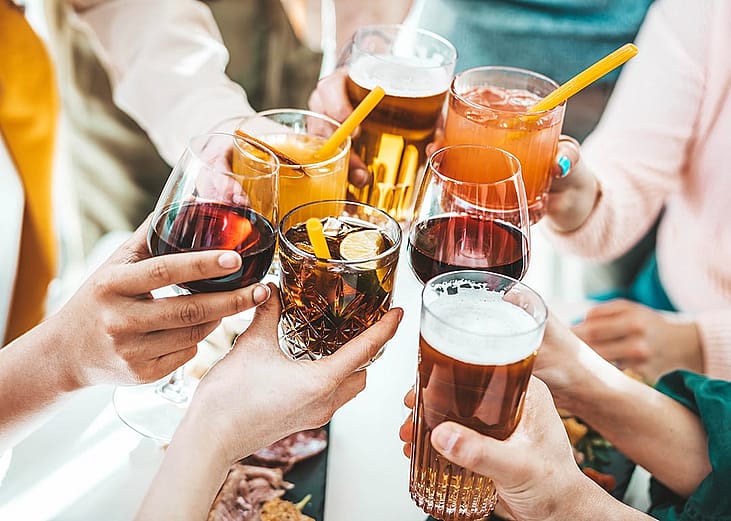 A close-up of young people holding cocktail glasses at a bar restaurant.