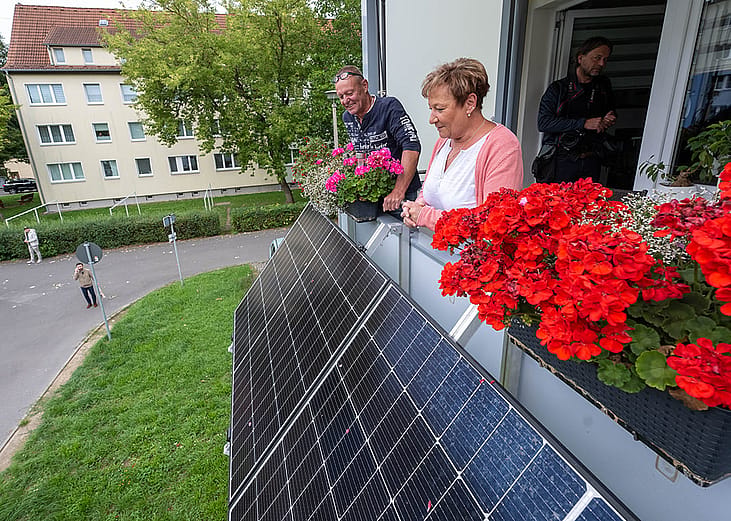 Tenants Kathrin Kother and Swen Bruske looking over their new balcony power plant with flower pots at their apartment in Taucha, Saxony, Germany.