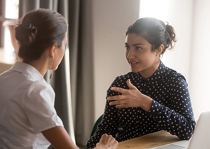 Coworkers sharing personal moments at work privately in a meeting room.
