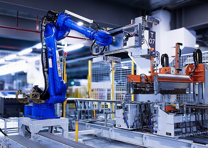 A blue robotic arm operating within a modern manufacturing machinery.