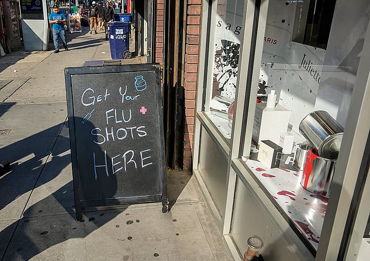 A sign in front of a drugstore advertising the availability of flu vaccines in New York, USA.