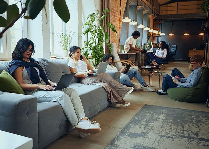Various professionals working separately on their own tasks inside a cozy and modern coworking space.