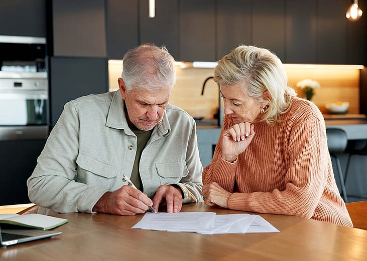 An elderly couple reviewing their financial plan documents and retirement savings in the dining table.