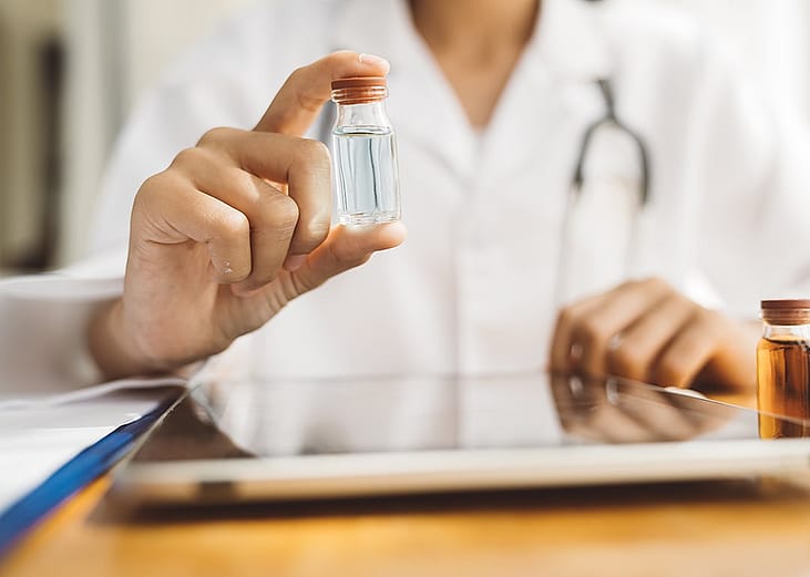 A doctor holding a liquid vial.