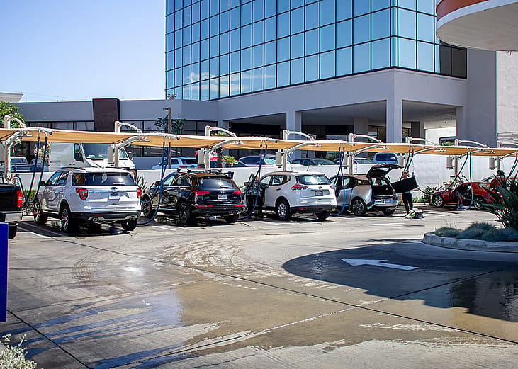 A view of several vehicles parked and waiting to get dried off at an automated car wash facility.