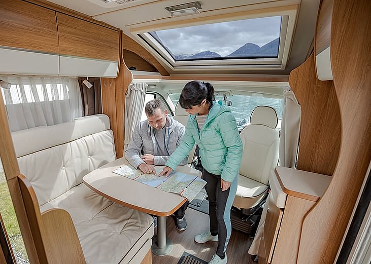 A couple inside an RV looking at a map.