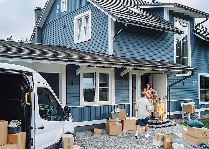 A family moving to a new house and unloading cargo boxes of their things from a van.