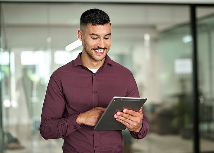 A businessman happily reviewing data from a tablet device.