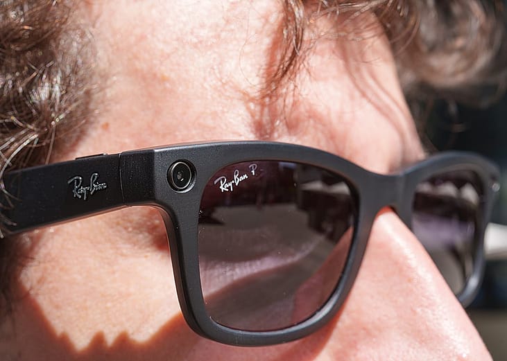 A person wearing Ray-Ban Meta smart glasses with integrated camera technology outdoors.