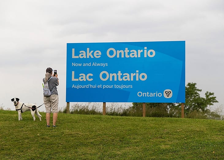 CANADA-ONTARIO-HAMILTON-LAKE ONTARIO-NAME A woman takes photos of an English-French bilingual sign reading "Lake Ontario Now and Always" at a lakeside conservation area in Hamilton, Ontario, Canada.