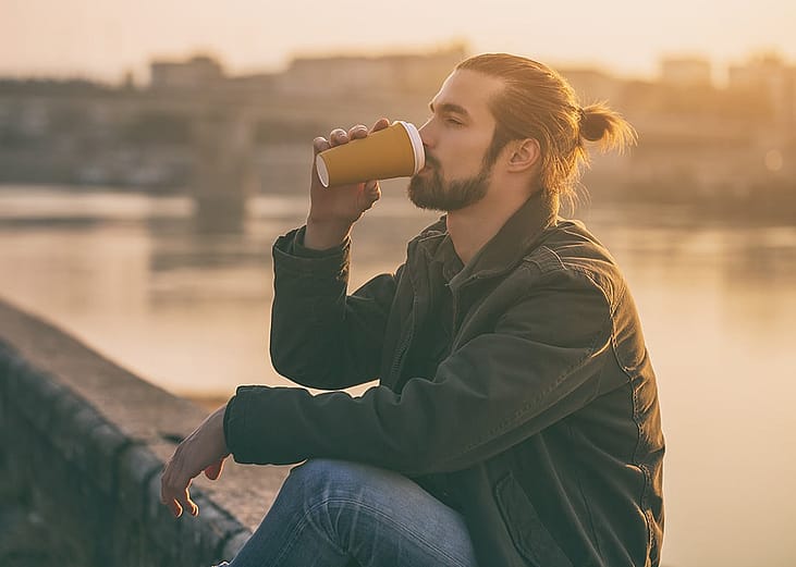 A man drinking coffee outdoors.