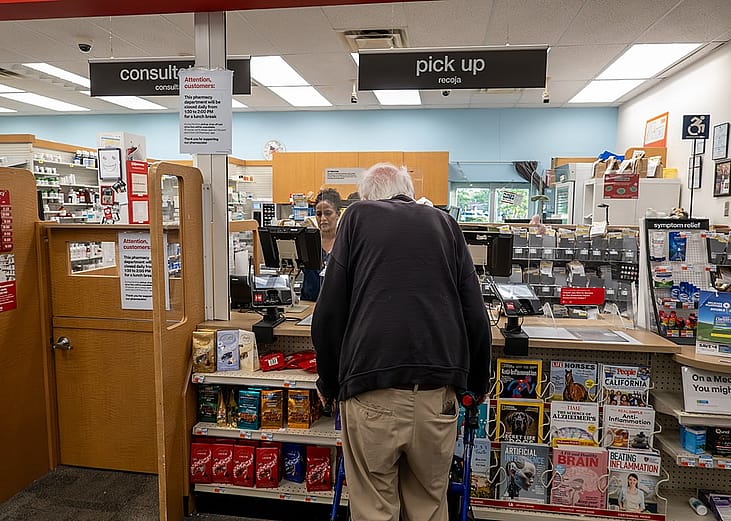 A senior person seen in line at a pharmacy counter.