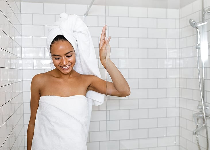 Young woman in white towels wrapped around head and body after shower.