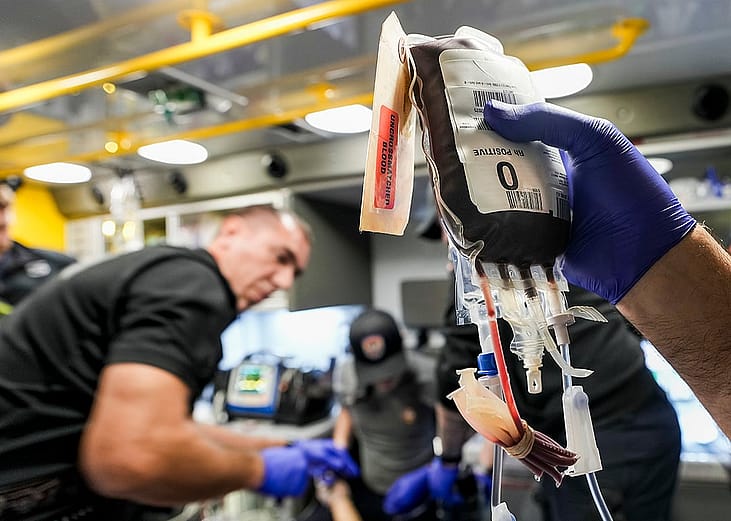 Fort Worth Fire Department Captain Trent Robinson works to transfuse a gunshot victim with a unit of blood in the back of an ambulance in Fort Worth on a late fall evening in 2025.