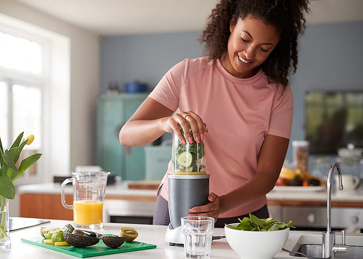 A woman at home making healthy juice drinks.